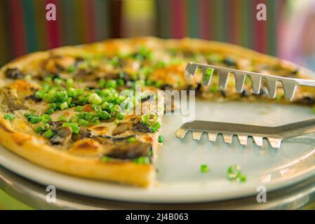 prendre des tranches de pizza. Table avec pizza dans un restaurant. Pizza et mains rapprochées sur fond vert. Banque D'Images