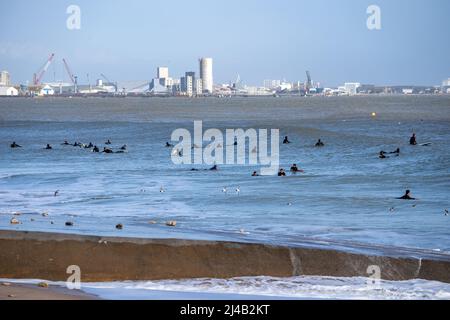 Silhouette de surfeur méconnue surfant sur les vagues près de la Pallice, le port commercial de la Rochelle. Quai commercial en arrière-plan Banque D'Images