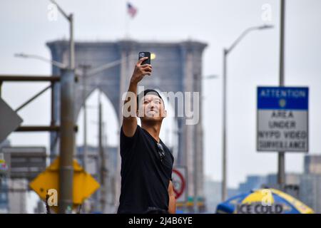 Les touristes reviennent à New York. Un touriste est vu prendre un selfie devant le pont de Brooklyn à New York le 13 avril 2022. Banque D'Images