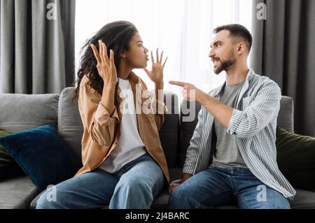 Couple jeune marié émotionnellement discuter de quelque chose, ils ont le problème. La femme afro-américaine et l'homme caucasien sont en désaccord les uns avec les autres ont un malentendu, ne peuvent pas prendre de décision, une querelle Banque D'Images