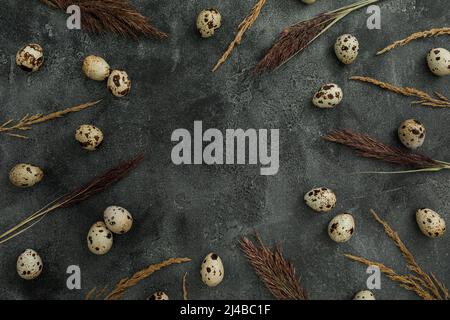 Concept de vacances de Pâques. Cadre avec œufs de Pâques et plumes sur fond sombre. Flat Lay, vue de dessus. Banque D'Images