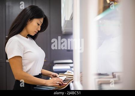 La décoratrice d'intérieur asiatique choisit la couleur du comptoir en pierre pour la cuisine ou les façades Banque D'Images