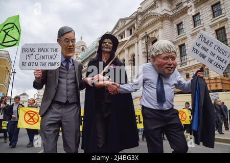 Londres, Royaume-Uni. 13th avril 2022. Les manifestants portant des masques Boris Johnson et Jacob Rees-Mogg se secouent la main avec un manifestant habillé comme le sinistre reapeur lors de la manifestation de la rébellion à Westminster. Des centaines de manifestants ont défilé dans le centre de Londres, exigeant que le gouvernement agisse sur la crise écologique et climatique. Crédit : SOPA Images Limited/Alamy Live News Banque D'Images