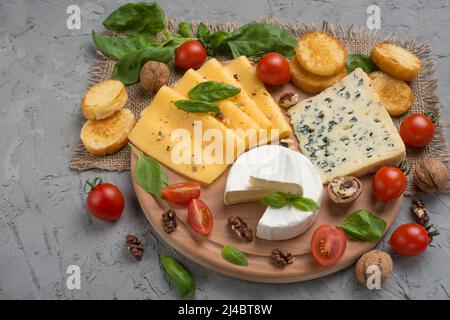 Différents types de fromages, avec basilic, tomates cerises, croûtons de baguettes.