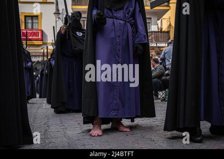 Séville, Espagne. 13th avril 2022. Un chrétien a vu marcher pieds nus dans les rues de Séville comme il prend part à une procession pendant le mercredi Saint pour marquer les célébrations de la semaine Sainte. La Fraternité de San Bernardo emmène dans les rues la procession d'el Cristo de la Salud et de la Virgen del Refugio après deux ans sans célébrer la semaine Sainte en raison des restrictions de la pandémie Covid-19. Crédit : SOPA Images Limited/Alamy Live News Banque D'Images