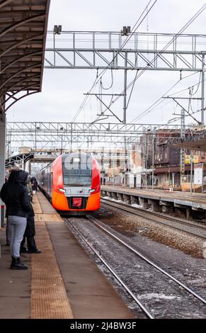 Le train à grande vitesse moderne se déplace rapidement le long de la plate-forme. Les gens attendent le train à la gare, les transports en commun. Banque D'Images