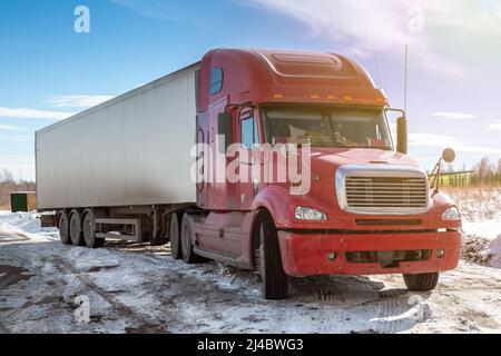 Camion à capot longue distance rouge avec semi-porteur blanc en campagne en hiver Banque D'Images