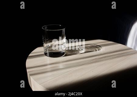Un verre d'eau potable vide et transparent est placé sur une table en bois brun clair. Image partiellement claire Banque D'Images