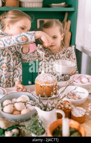 Bonne famille Candid petits enfants sœurs filles ensemble ont l'amusement prêt printemps vacances de Pâques à la maison dans la cuisine décorant table et les gâteaux de Pâques b Banque D'Images