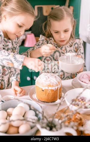 Bonne famille Candid petits enfants sœurs filles ensemble ont l'amusement prêt printemps vacances de Pâques à la maison dans la cuisine décorant table et les gâteaux de Pâques b Banque D'Images