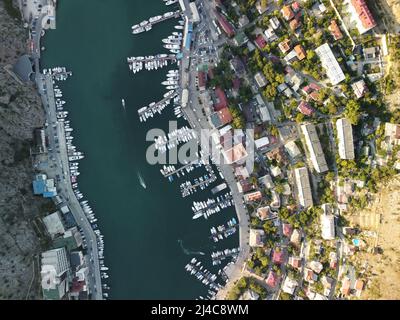 Vue panoramique aérienne du paysage de Balaklava avec des bateaux et la mer dans la baie de la marina au coucher du soleil. Attraction touristique de Crimée Sébastopol. Vue de dessus de drone Banque D'Images