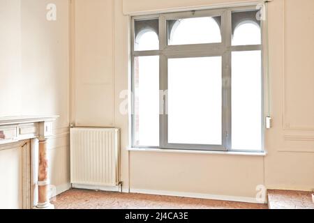 Appartement vide avec fenêtres et cheminée en marbre avant rénovation Banque D'Images
