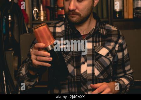 Cocktail barman barbu focalisé dans un shaker au bar Banque D'Images