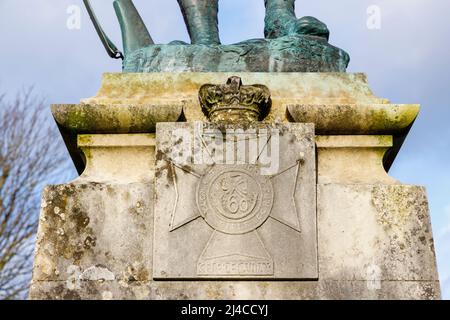 Cimier à la base de la statue en bronze commémorative d'un rifleman du Royal Rifle corps à Cathedral Close, Winchester, Hampshire Banque D'Images