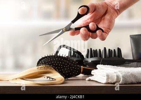 Coiffeur avec ciseaux à la main et outils sur la table avec étagères avec fournitures de coiffure en arrière-plan. Vue avant. Composition horizontale. Banque D'Images