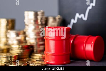 Des barils rouges, des piles d'argent et une courbe montante symbolisent les prix élevés du carburant Banque D'Images