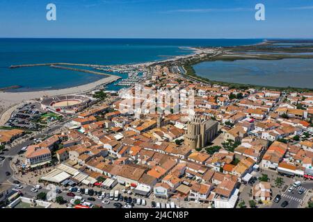 Tir de drone, photo de drone de Saintes-Maries-de-la-Mer avec la vieille ville, le port, l'église notre Dame et les champs de sel en arrière-plan, département Banque D'Images