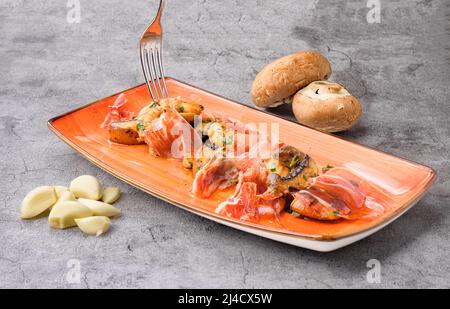 Délicieux repas avec des tranches de jambon serrano, des champignons et des crevettes sur l'assiette Banque D'Images