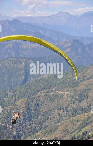 Vue arrière d'un voyageur mâle non identifié qui profite du parapente avec un pilote professionnel dans l'Himachal Pradesh. Banque D'Images