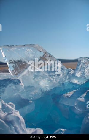 Morceaux de glace couchés sur la glace lisse idéale de baikal avec des hummocks de glace à l'horizon. Le soleil brille à travers les côtés des glaçons. Les floes ressemblent à Banque D'Images