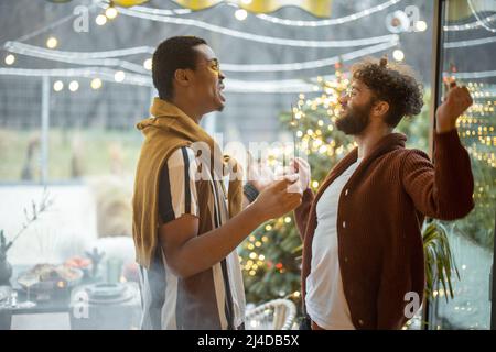 Deux amis masculins célébrant avec des spameurs à l'arrière-cour Banque D'Images