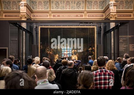 Les visiteurs admirent la veille nocturne de Rembrandt derrière son verre protecteur au Rijksmuseum à Amsterdam, aux pays-Bas. Banque D'Images