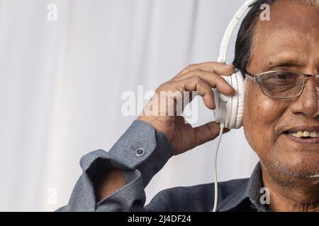 Gros plan d'un vieil Indien aime la musique avec un casque blanc Banque D'Images