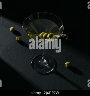 Verre de cocktail classique de martini sec avec olives sur table en pierre sombre Banque D'Images