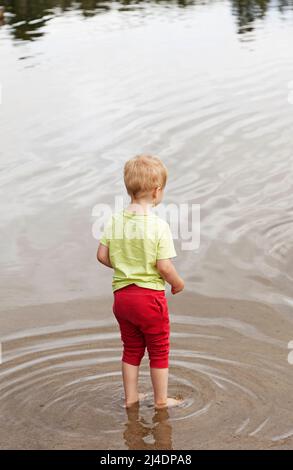 Umea, Norrland Suède - 23 juin 2021 : un petit homme se tient dans l'eau au bord de la mer Banque D'Images