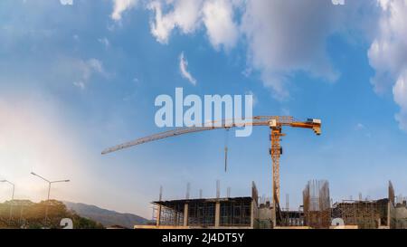 Chantier de construction avec grues sur fond du ciel et du soleil. Banque D'Images