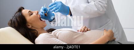 Dentiste traitant les dents de la jeune femme enceinte patient couché Clinique Banque D'Images