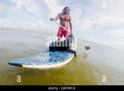 Aurora province, Philippines. 14th avril 2022. Surfeur Mario Cardama Jr. Et chien Gordy surfent sur une plage dans la province d'Aurora, aux Philippines, le 14 avril 2022. Fondé en 2016, le collectif de chiens se compose d'amateurs de surf qui sont également des amoureux de chiens. Ils passent leur temps libre à enseigner à leurs animaux de compagnie adoptifs à monter à bord d'une planche de surf dans la municipalité de Baler, dans la province d'Aurora, qui est connue localement comme « le berceau du surf philippin ». Crédit: Rouelle Umali/Xinhua/Alamy Live News Banque D'Images