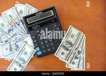 Calculatrice et 100 dollars sur table en bois. Banque D'Images