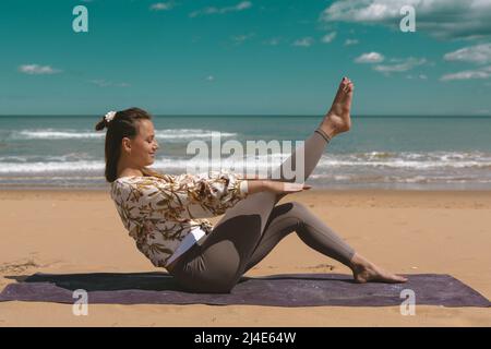 jeune femme faisant de l'exercice pilates sur la plage Banque D'Images