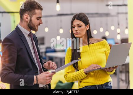 Le responsable explique à son employé comment terminer ses tâches. Collègues discutant d'un projet en se tenant dans un bureau. Banque D'Images