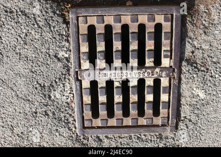 Nitra, Slovaquie - 07.15.2021: Grille en fonte sur le drain. Grille en fonte sur le canal de drainage. Grille d'évacuation d'eau de pluie sur chaussée en pierre. Banque D'Images