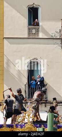 Séville, Espagne; 14 avril 2022: Les gens qui regardent une procession de leurs balcons pendant la semaine sainte. Fraternité de 'Las Cigarreras' Banque D'Images