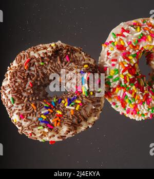 Prise de vue macro. Deux délicieux beignets au glaçage au sucre et aux confiseries multicolores. Isolé sur un fond gris. Nourriture douce, enfant préféré Banque D'Images