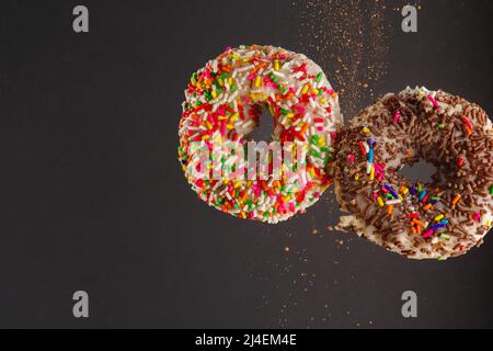 Deux beignets sucrés avec glaçage au sucre et confiseries multicolores saupoudrés dans un vol gelé sur fond gris. Nourriture calorique douce, vacances, birt Banque D'Images