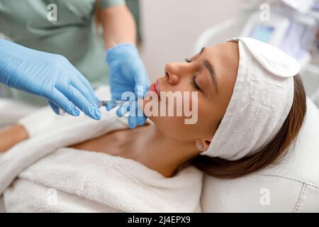 Jeune femme recevant une injection d'acide hyaluronique dans un salon de beauté Banque D'Images