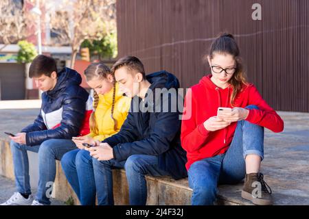 Adolescents absorbés dans les téléphones à l'extérieur Banque D'Images