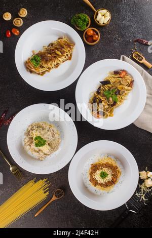 un ensemble de spaghetti aux pâtes avec sauce, tranche de bœuf, huile d'olive et persil vert frais dans une assiette ovale blanche avec ingrédients sur fond noir Banque D'Images