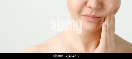 Une femme souffrant de fortes douleurs dentaires, touchant la joue avec la main. Concept de dentisterie. Banque D'Images