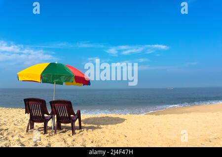 Chaises de plage sur la plage de sable blanc avec ciel bleu nuageux et soleil. Deux chaises sous un parapluie à la plage de Marai à Kerala Inde Banque D'Images