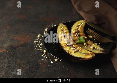 Concept de nourriture savoureuse avec des bananes grillées sur fond texturé foncé Banque D'Images