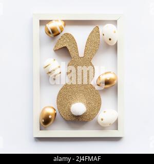 lapin de pâques et œufs dorés sur fond blanc dans un cadre. Happy Easter minimal concept, carte de vœux. Mise au point sélective. Banque D'Images