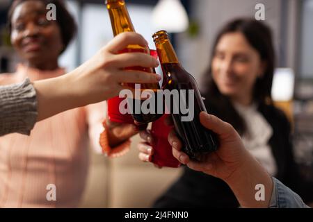 Les employés de bureau font des toasts et des verres de clinking d'alcool, prenant des boissons après les heures de travail. Des gens joyeux qui apprécient le champagne, le vin ou la bière, font des cheers à la fête. Gros plan. Banque D'Images