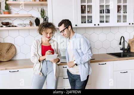 Des partenaires d'affaires jeunes et intelligents travaillent sur un projet dans un bureau moderne, discutant des idées. Des collègues heureux étudiant des tableaux financiers Banque D'Images