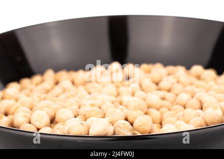 Plusieurs grains de houmous non cuits dans une plaque en céramique noire, en gros plan, isolés sur du blanc. Banque D'Images