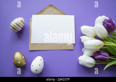Vœux de Pâques : espace de copie de lettre papier sur fond violet. Bouquet de tulipes blanches et œufs de pâques dorés et à motifs. Banque D'Images